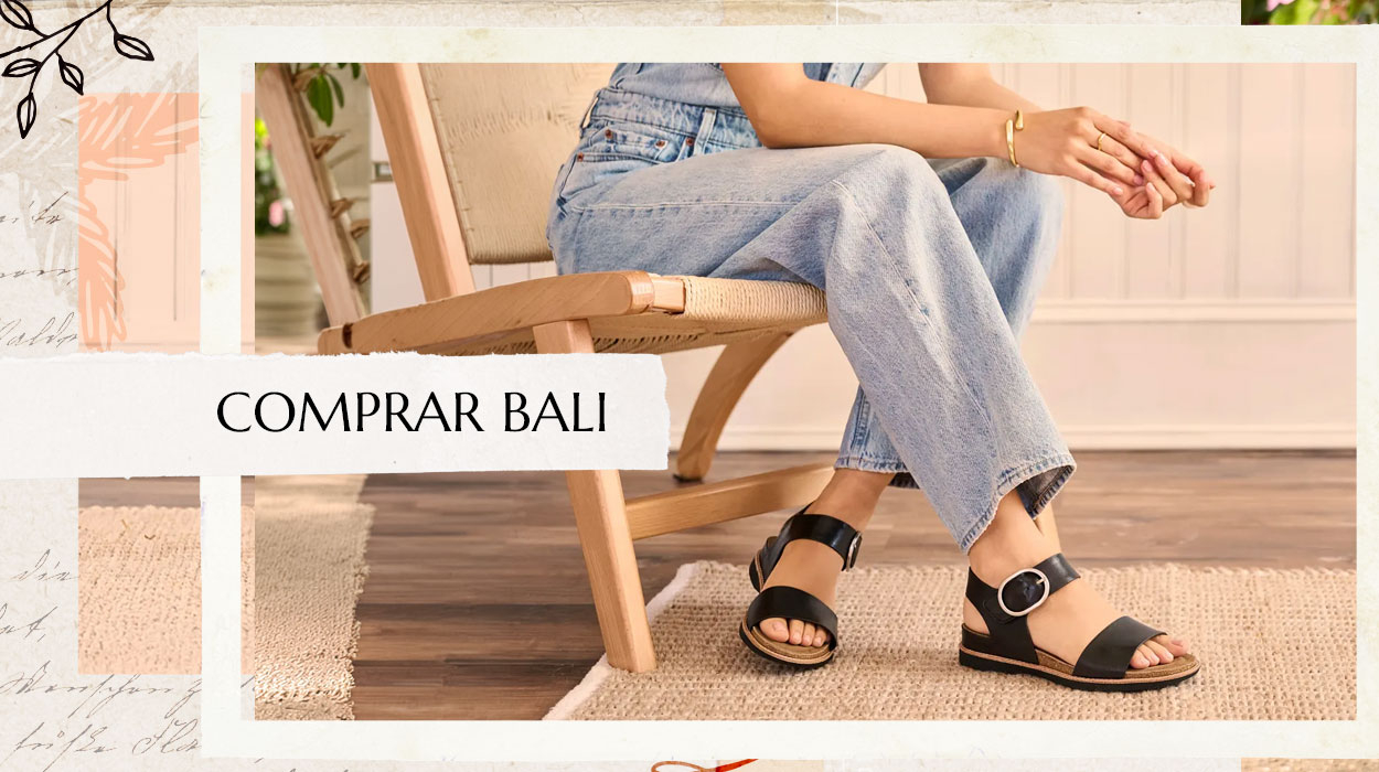 Mujer sentada en una silla con vaqueros azules y sandalias Bali negras. Compra las Bali.
