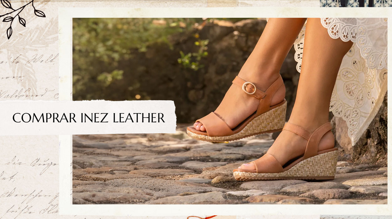 Mujer sentada con un vestido blanco, luciendo el modelo Inez de cuero en color tostado. Comprar Inez Cuero.