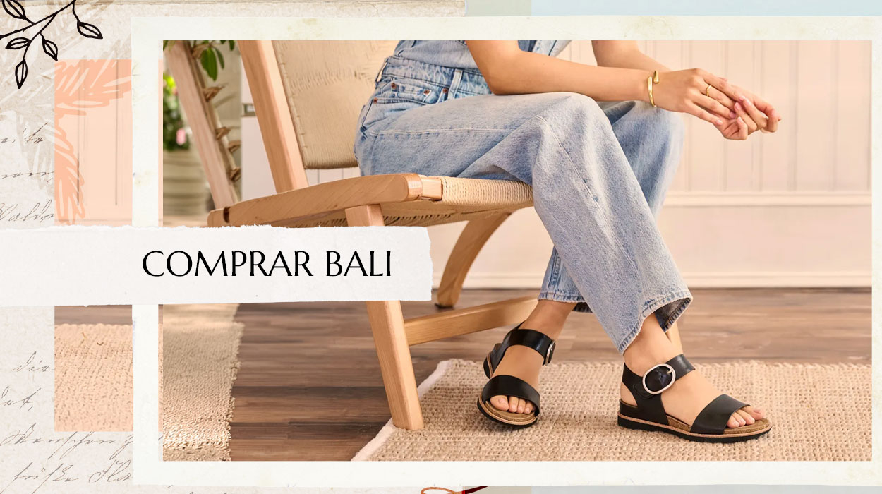 Mujer sentada en una silla con vaqueros azules y sandalias Bali negras. Compra las Bali.