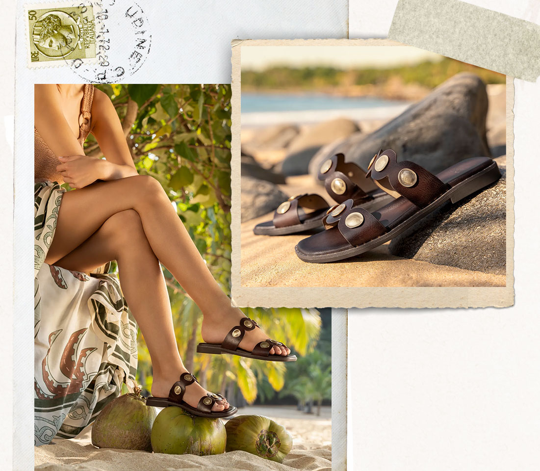 Woman sitting on a beach in a paisley dress, Featuring the Ezra sandal in brown.